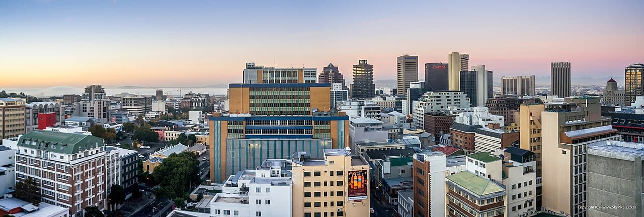Cape Town skyline at dusk with Table Mountain behind it.